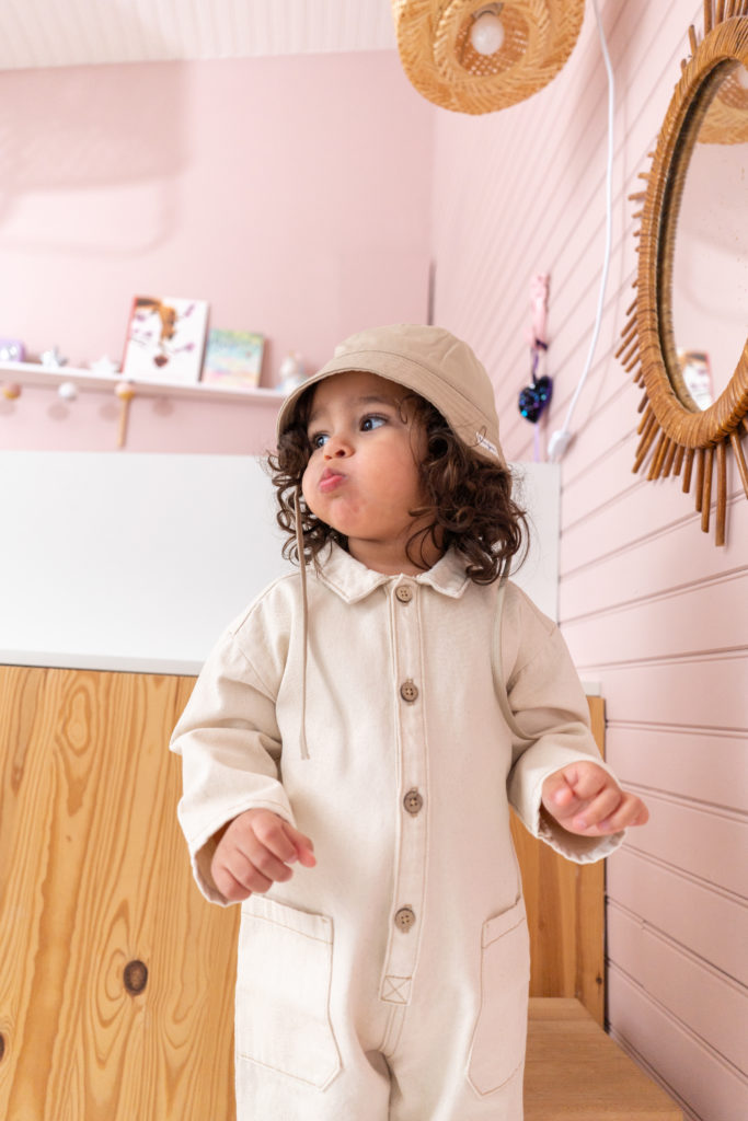 Enfant qui souffle avec un chapeau et combinaison beige