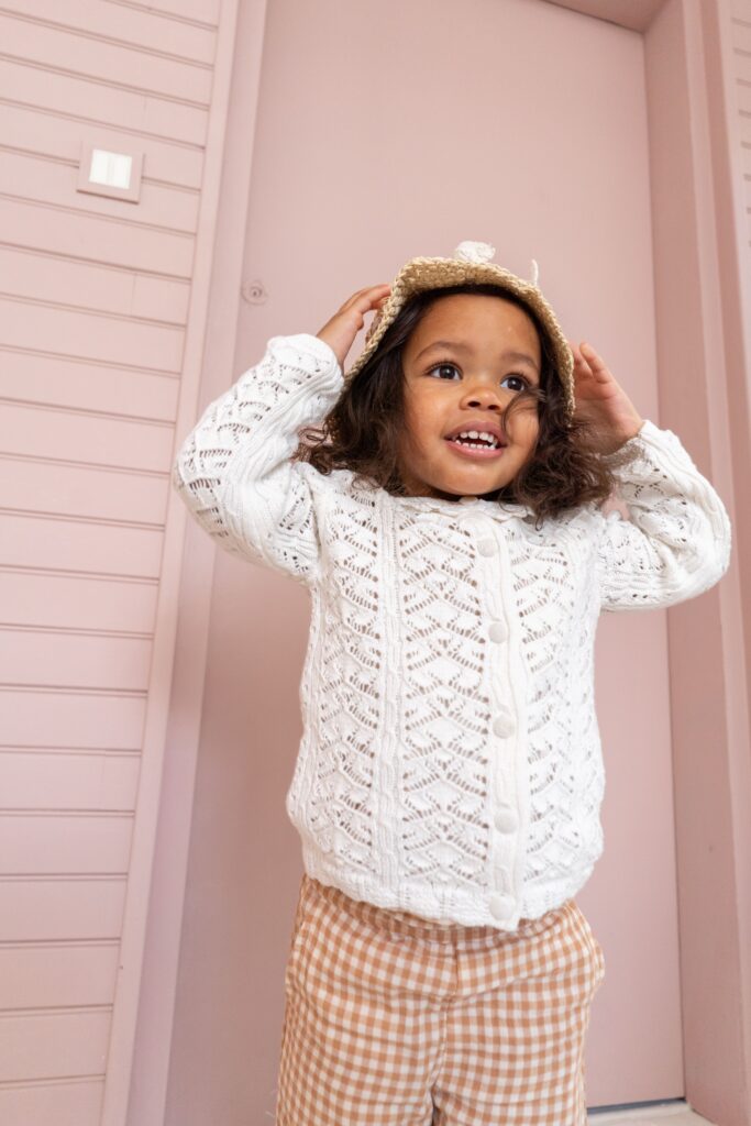 petit fille avec un gilet en maille et un chapeau