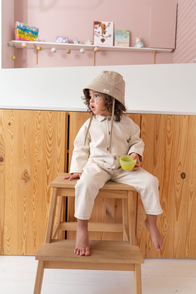 petit garçon avec une combinaison beige assis sur un tabouret
