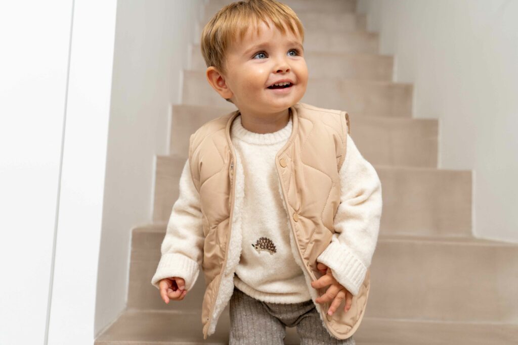 Petit garçon qui descend les escaliers avec une veste sans manches