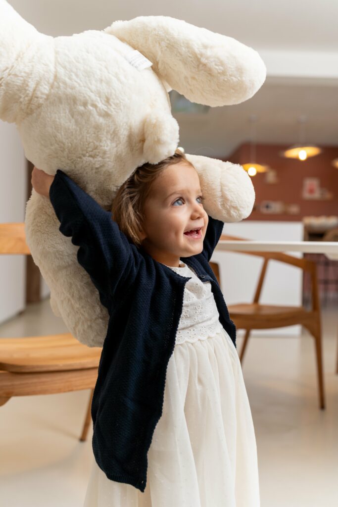 petit fille qui tient un nounourse au dessus de sa tête